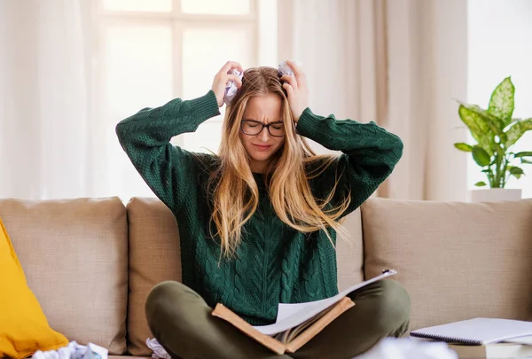 Une étudiante malheureuse assise sur un canapé, étudiant . — Photo