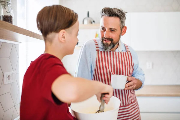 Mogen far med liten son inomhus i köket, gör pannkakor. — Stockfoto