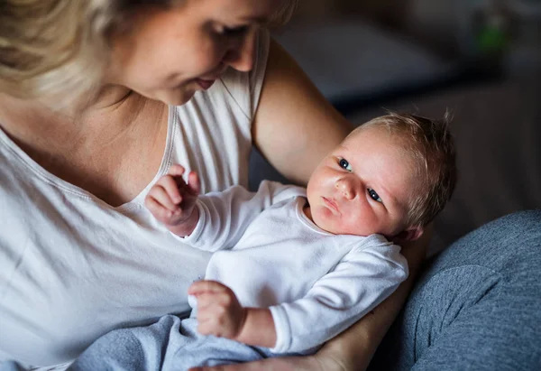 Eine schöne junge Mutter mit einem Neugeborenen zu Hause. — Stockfoto