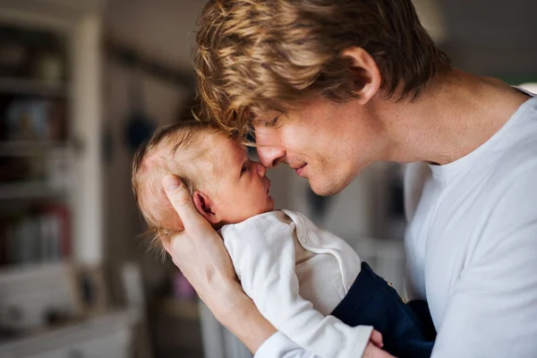 Een jonge vader met een pasgeboren baby zoon thuis. — Stockfoto