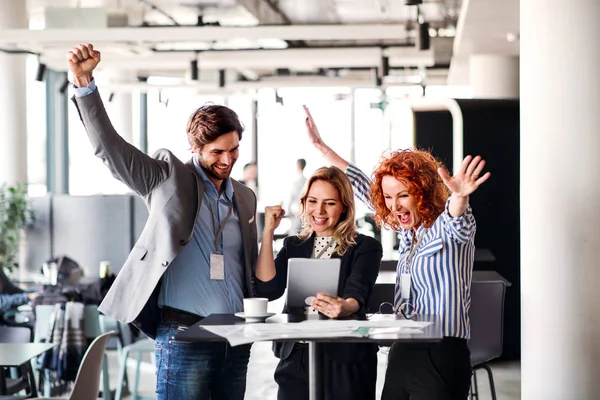 Un groupe de gens d'affaires debout dans un bureau, exprimant l'excitation . — Photo