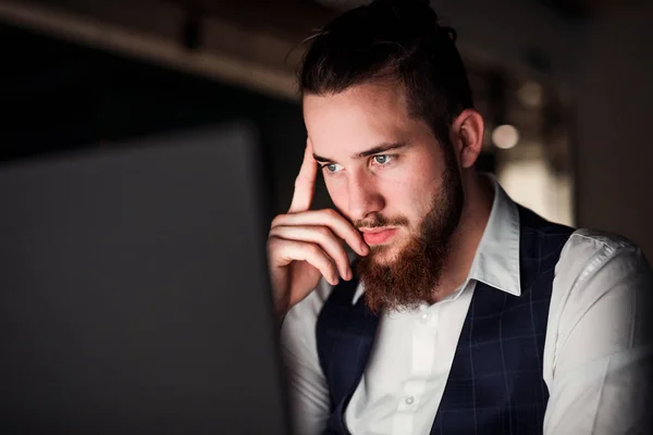 Ett porträtt av ung affärsman med dator på ett kontor, som arbetar. — Stockfoto