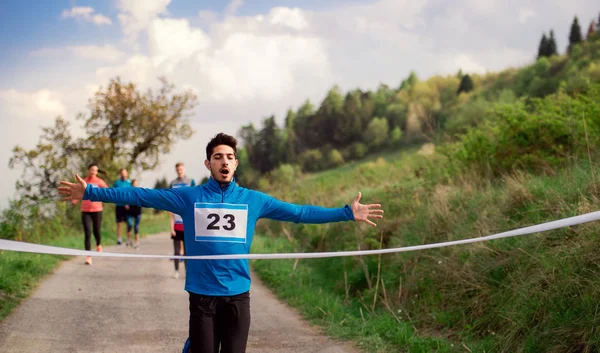 Hombre corredor cruzar la línea de meta en una competición de carreras en la naturaleza . — Foto de Stock