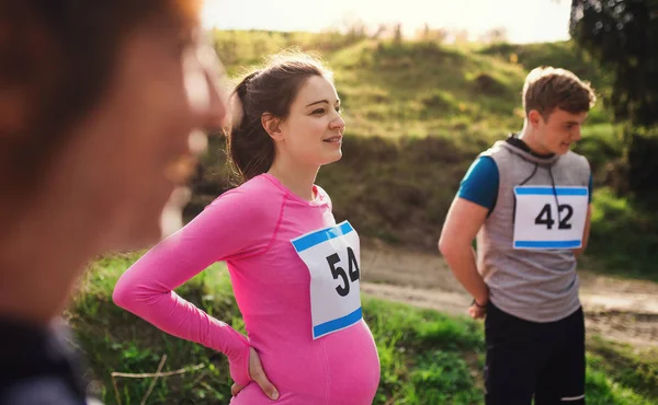 Fit i aktywny Pregant kobieta z przyjaciółmi robi ćwiczenia w przyrodzie. — Zdjęcie stockowe