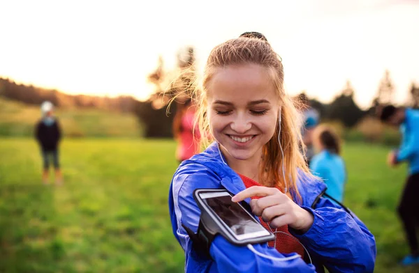 Un portrait de jeune femme avec smartphone faisant de l'exercice dans la nature . — Photo