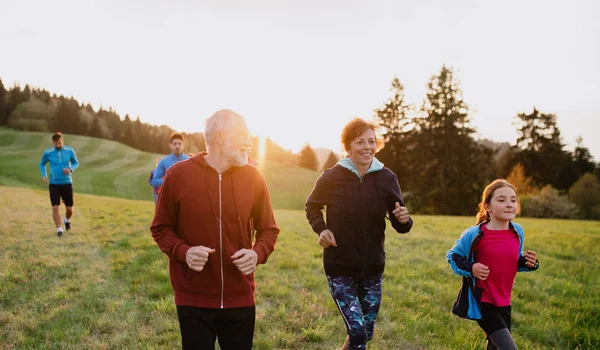 En stor grupp människor korsar land som springer i naturen. — Stockfoto