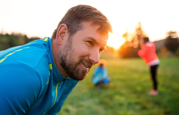 Porträt eines jungen Mannes mit einer großen Gruppe von Menschen, die in der Natur Sport treiben. — Stockfoto