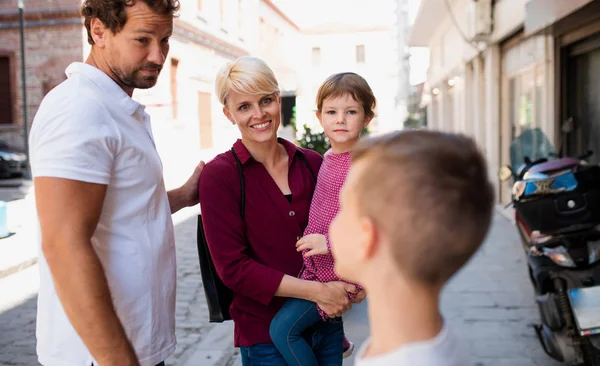 Jeune famille avec deux jeunes enfants debout à l'extérieur en ville en vacances . — Photo