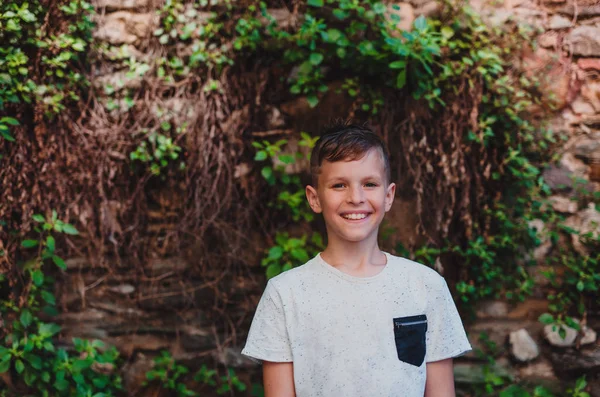 Porträt eines kleinen Jungen, der draußen vor einer alten Ziegelmauer steht. — Stockfoto