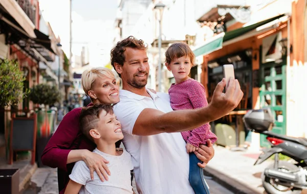 Eine junge Familie mit zwei kleinen Kindern steht draußen in der Stadt und macht ein Selfie. — Stockfoto