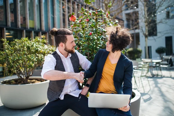 Junge Geschäftsleute mit Laptop im Hof und schütteln Hände. — Stockfoto