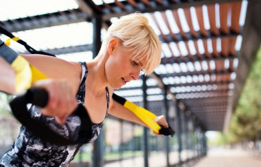 Trx fitness ile egzersiz yapan genç bir sporcu açık havada kayışları.
