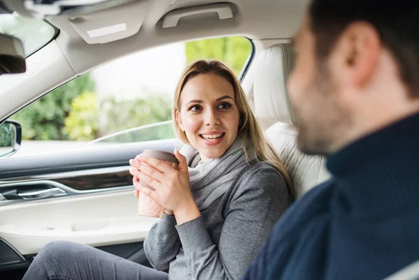 Happy Young par med kaffe sitter i bilen, pratar. — Stockfoto