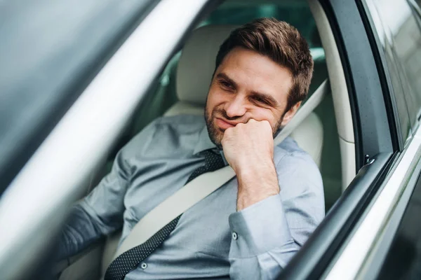 Junger gelangweilter Geschäftsmann mit Hemd und Krawatte sitzt im Auto. — Stockfoto