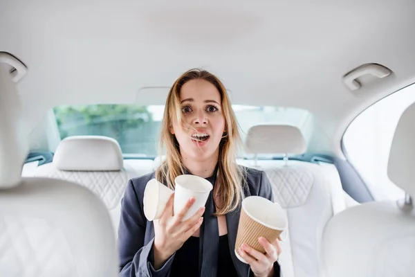 Young frustrated woman with empty paper glasses sitting in car. — Stock Photo, Image