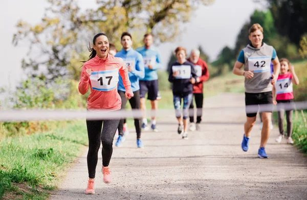 Large group of multi generation people running a race competition in nature.