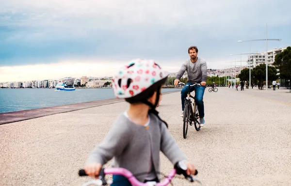 Vater und kleine Tochter mit Fahrrädern im Freien am Strand. — Stockfoto