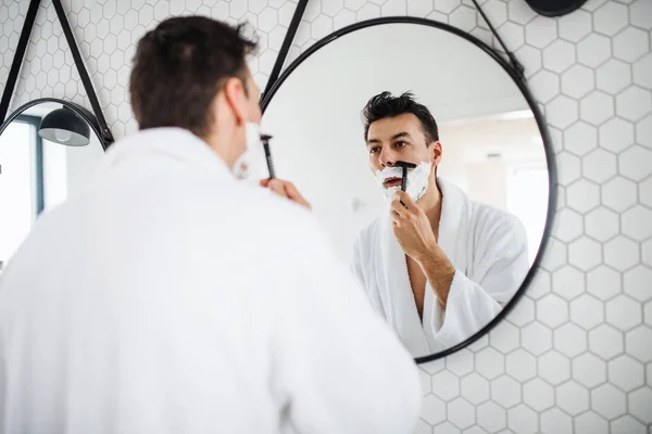 Junger Mann rasiert sich morgens im Badezimmer, Tagesablauf. — Stockfoto