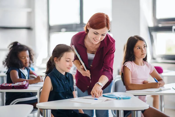 Un insegnante che cammina tra i bambini delle piccole scuole durante la lezione, spiegando . — Foto Stock