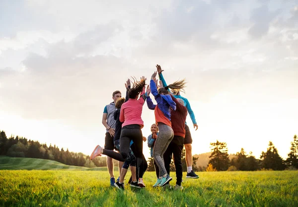 Gran grupo de personas en forma y activas saltando después de hacer ejercicio en la naturaleza . — Foto de Stock
