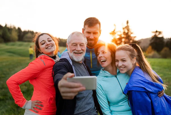 Um grupo de pessoas aptas e ativas descansando depois de fazer exercício na natureza, tomando selfie . — Fotografia de Stock
