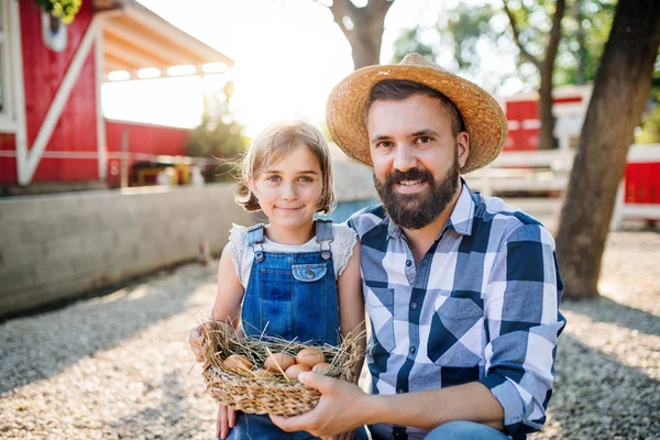 Vater mit kleiner Tochter im Freien auf Familienbauernhof mit Eiern. — Stockfoto