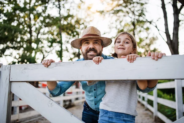A portrait of father with small daughter outdoors on family farm. — Stock Photo, Image