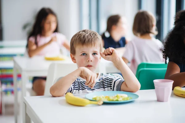 食堂で陽気な小さな学校の子供たちのグループ, 昼食を食べて. — ストック写真