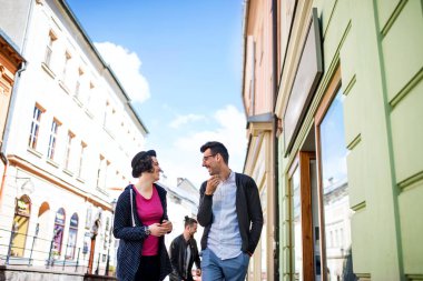 Bir grup genç arkadaş şehirde açık havada yürürken, konuşuyorlar..