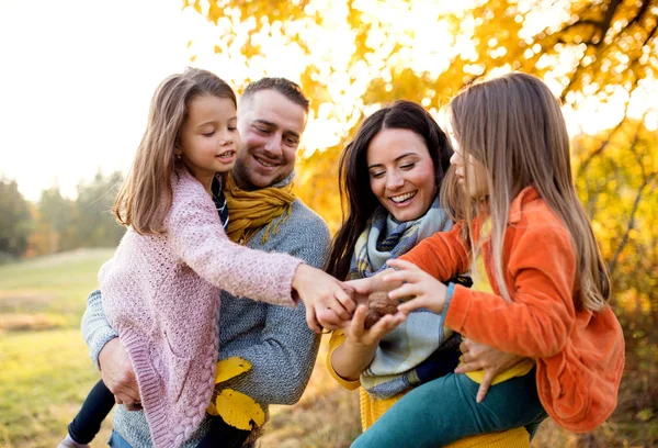 Um retrato de família jovem com duas crianças pequenas na natureza de outono . — Fotografia de Stock