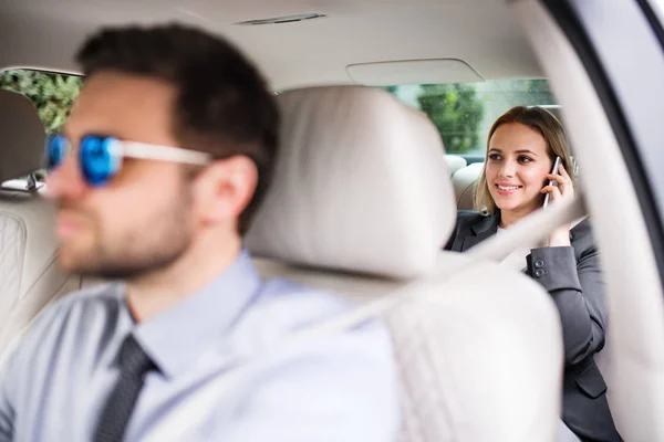 Affärskvinna med smartphone sitter på baksätet i taxi bil, talar. — Stockfoto