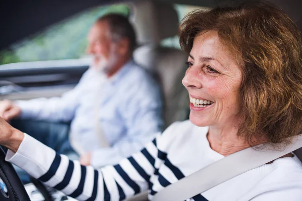 Glückliches Seniorenpaar sitzt im Auto, fährt und spricht. — Stockfoto