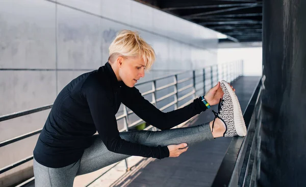 Porträt einer jungen Sportlerin, die im Freien Sport treibt, sich dehnt. — Stockfoto