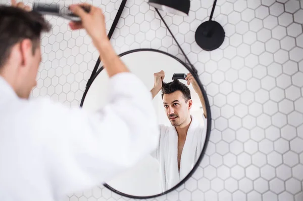 Young man combing hair in the bathroom in the morning, daily routine. — Stock Photo, Image