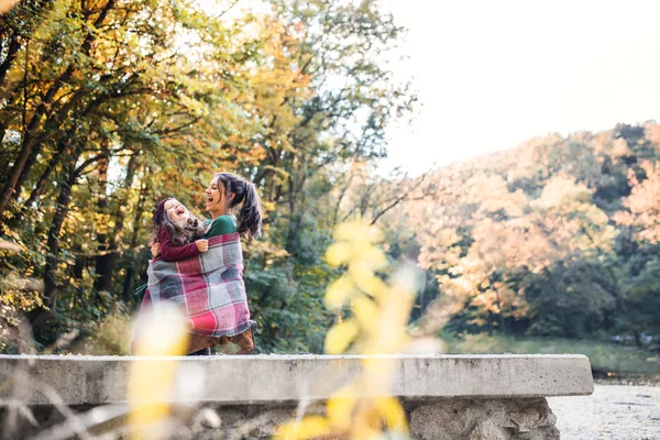Een jonge moeder met een dochter van de peuter met plezier in bos in de herfst natuur. — Stockfoto