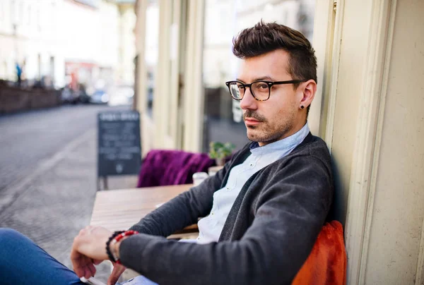 Ung sorglig och seriös man sitter i ett utomhus kafé. — Stockfoto