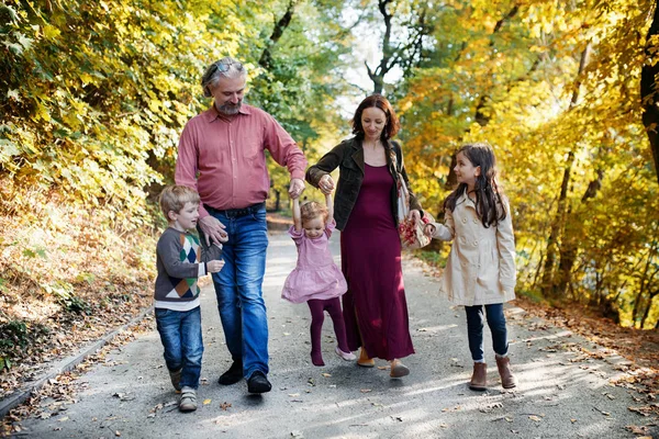 Belle jeune famille avec de jeunes enfants lors d'une promenade dans la forêt d'automne. — Photo