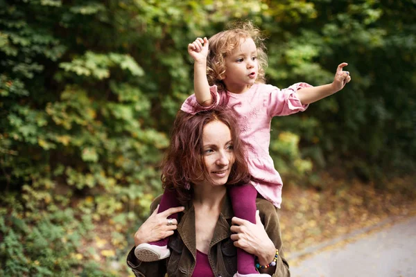 Mooie jonge moeder met peuter dochter op een wandeling in herfst bos. — Stockfoto