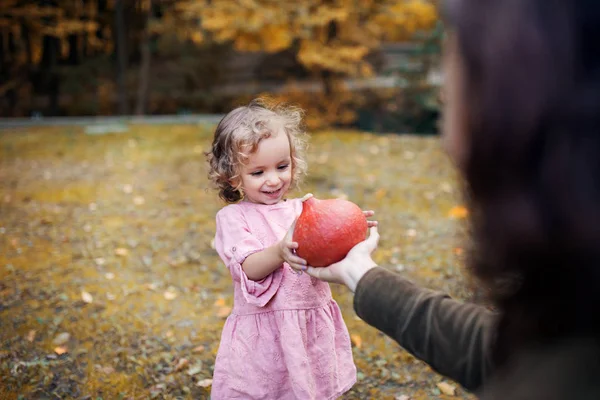 Pequeña niña con madre en un paseo por el bosque de otoño, sosteniendo calabaza hokkaido . — Foto de Stock