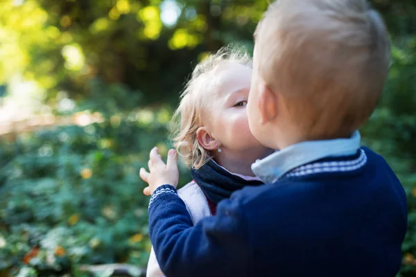 Twin criança irmão menino e menina de pé na floresta de outono, beijando . — Fotografia de Stock