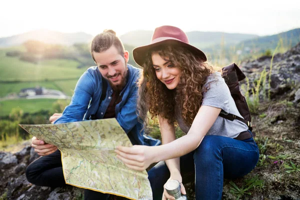 Mladí turisté, kteří cestují s batohy v přírodě, používají mapu. — Stock fotografie
