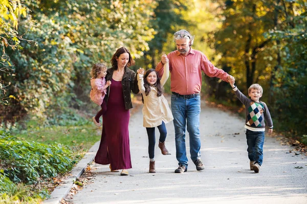 Schöne junge Familie mit kleinen Kindern auf einem Spaziergang im Herbstwald. — Stockfoto