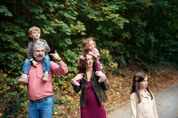 Schöne junge Familie mit kleinen Kindern auf einem Spaziergang im Herbstwald. — Stockfoto