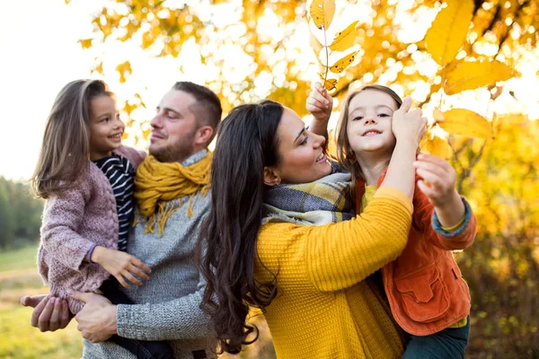 A portrait of young family with two small children in autumn nature. — Stock Photo, Image