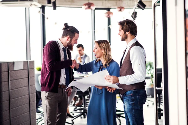 Un groupe de jeunes gens d'affaires dans un bureau, serrant la main . — Photo