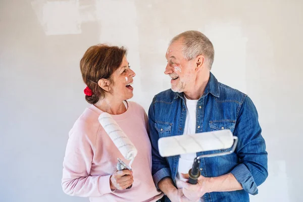 Coppia di anziani che dipinge pareti in una nuova casa, divertendosi. Concetto di delocalizzazione . — Foto Stock