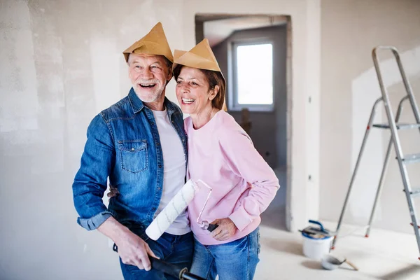 Ένα ζευγάρι που ζωγραφίζει τοίχους σε νέο σπίτι, γελώντας. Έννοια της μετεγκατάστασης. — Φωτογραφία Αρχείου