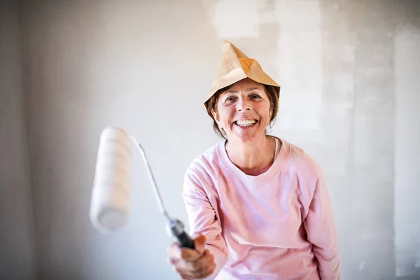 Mujer mayor pintando paredes en un nuevo hogar, divirtiéndose. Concepto de reubicación . —  Fotos de Stock