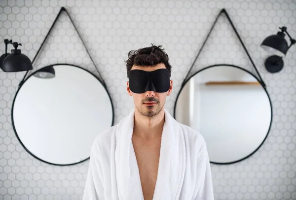 Junger Mann mit Augenmaske morgens im Badezimmer. — Stockfoto