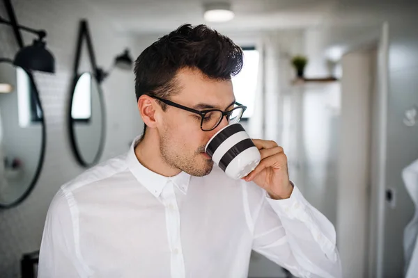 Hombre joven con camisa blanca en el baño por la mañana, bebiendo café . —  Fotos de Stock
